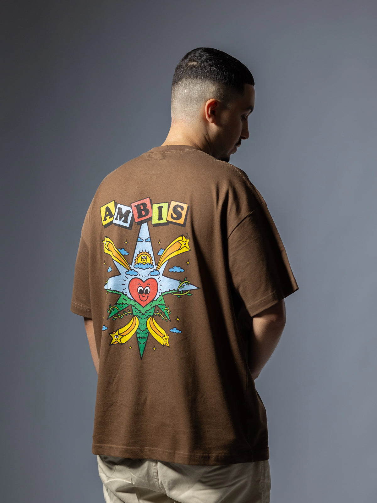 Dos d'un t-shirt oversize marron Ambis avec une rose des vents multicolore et un cœur au centre