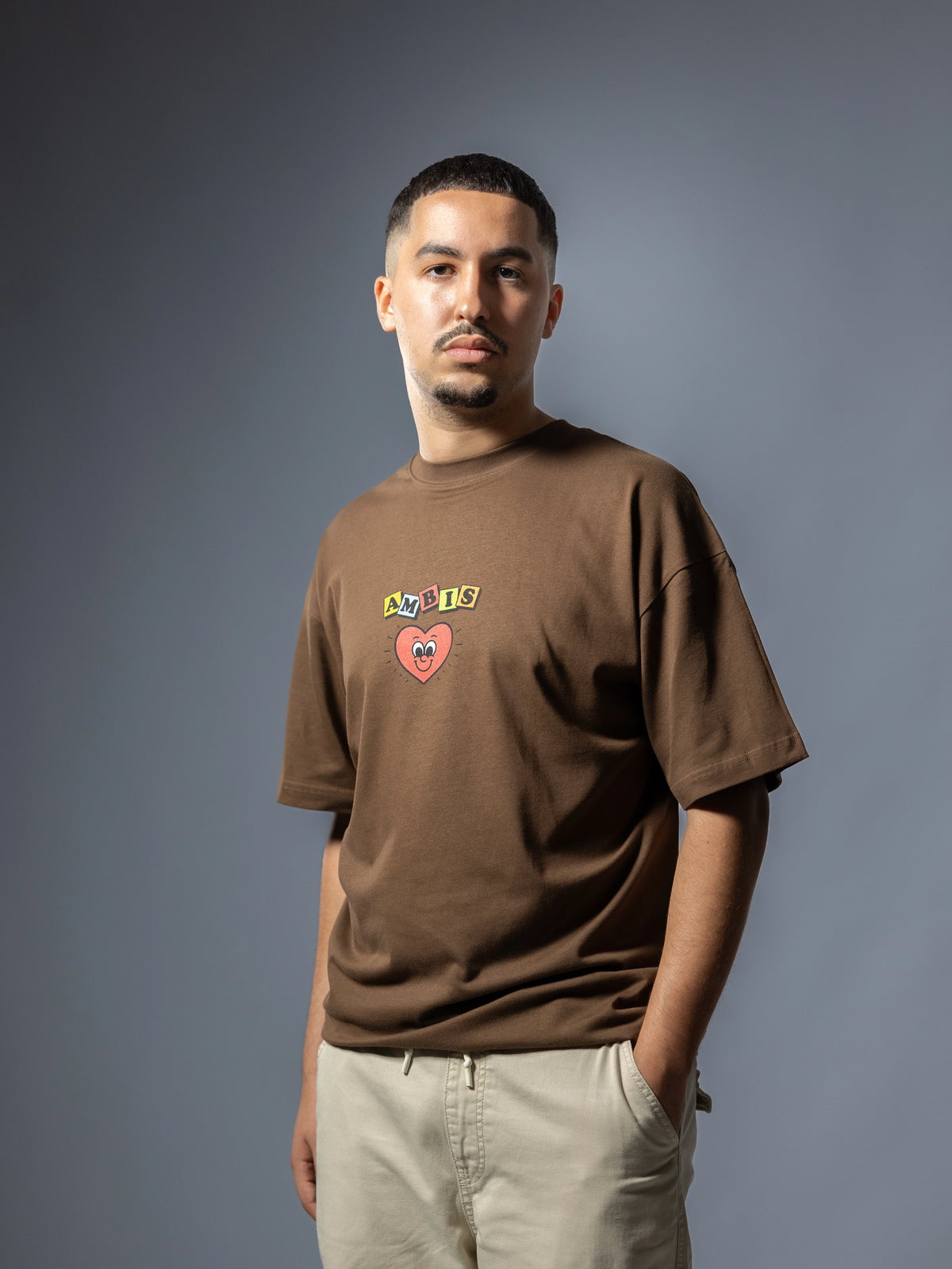 Face d'un t-shirt oversize marron Ambis avec le logo Ambis en couleur et un cœur au centre