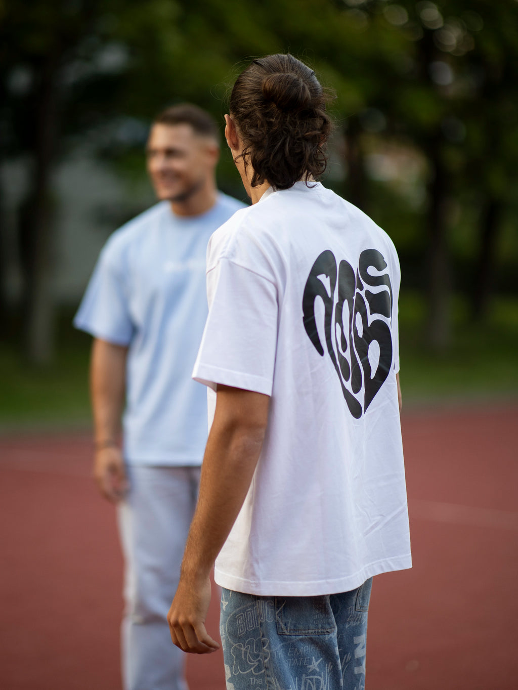 Homme portant un t-shirt oversize blanc Ambis avec un cœur imprimé au dos